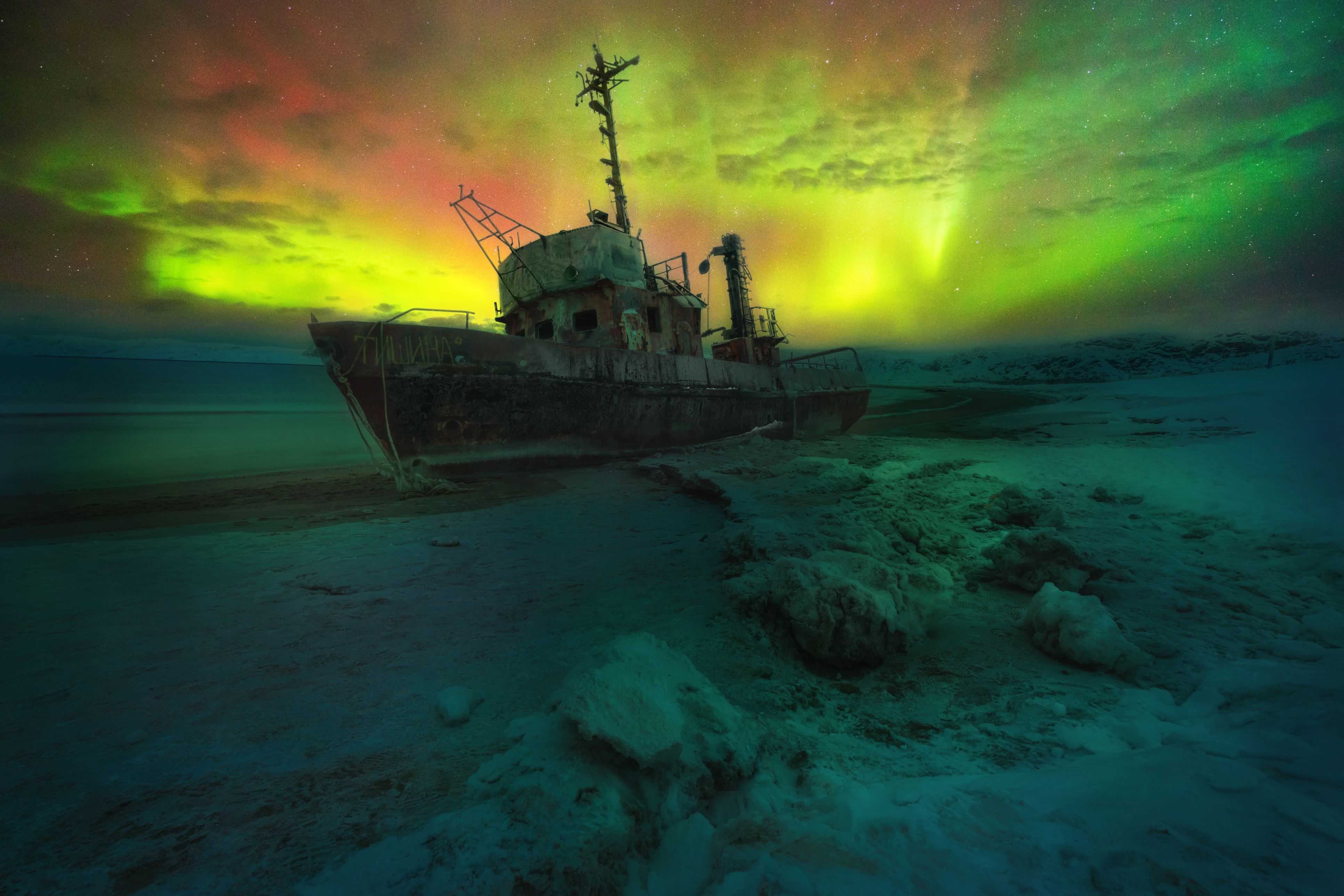 Aurora borealis at the coast of Barents sea with rack of ship, Teriberka, Russia