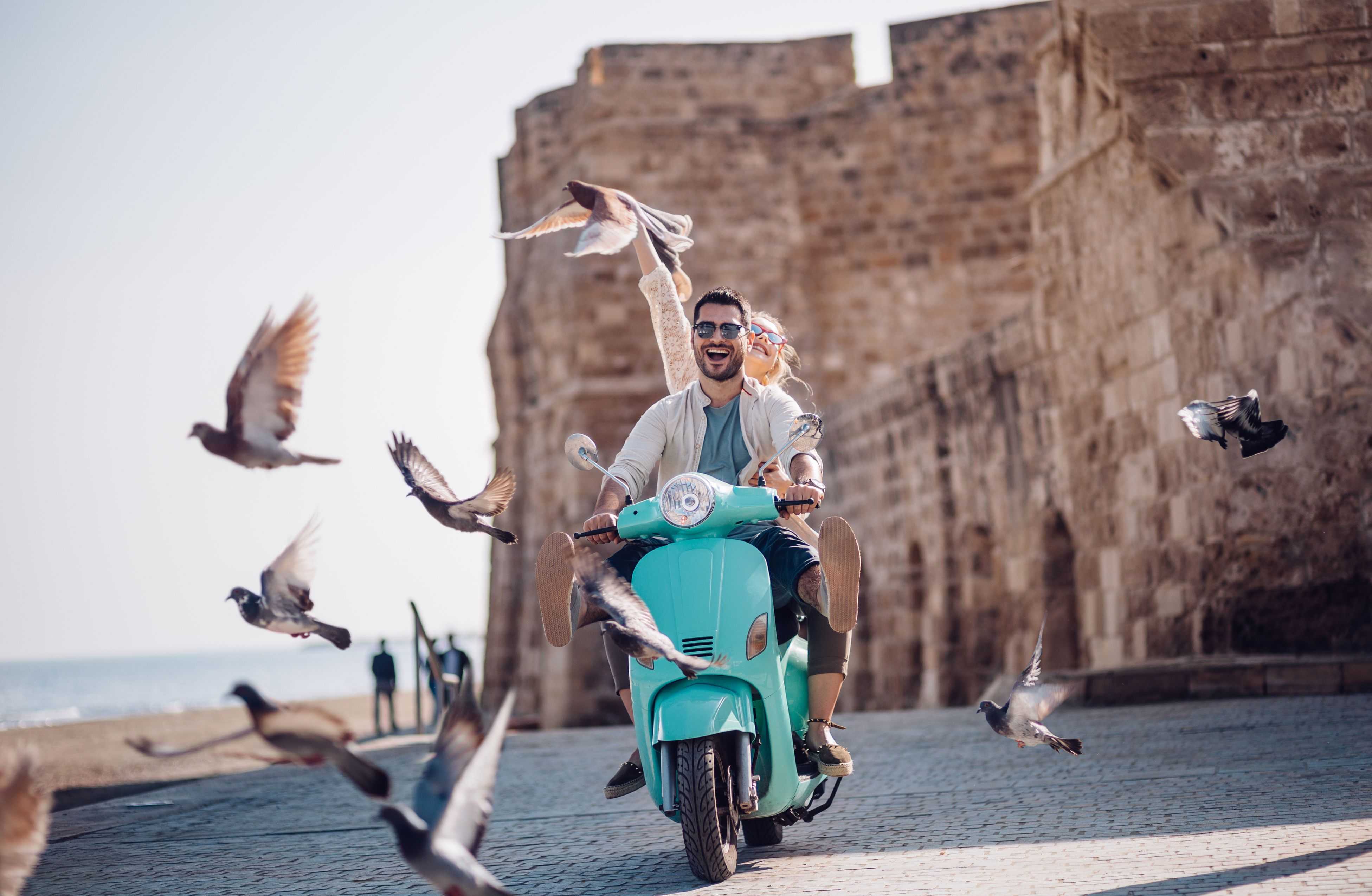 Fun riding retro scooter by the sea in Greece